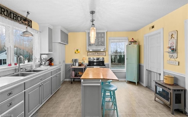 kitchen with sink, gray cabinetry, a kitchen breakfast bar, and stainless steel electric range