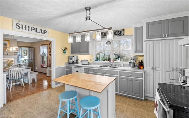 kitchen with gray cabinets, a kitchen island, a breakfast bar area, electric range, and a textured ceiling