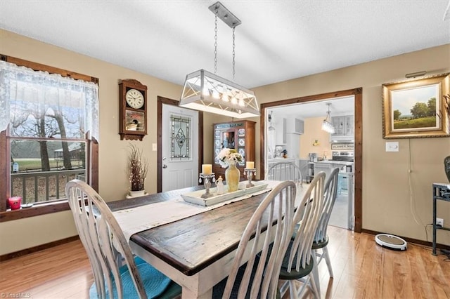 dining area featuring a notable chandelier, a textured ceiling, and light wood-type flooring