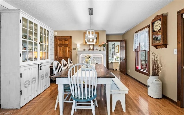 dining space with a textured ceiling, light hardwood / wood-style floors, and a healthy amount of sunlight