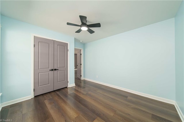 unfurnished bedroom featuring ceiling fan, a closet, baseboards, and dark wood-style floors