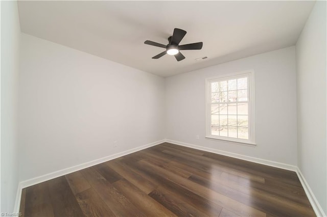 spare room with baseboards, visible vents, dark wood-style flooring, and ceiling fan