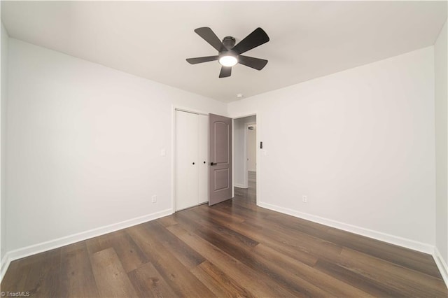 empty room featuring a ceiling fan, baseboards, and dark wood-style flooring