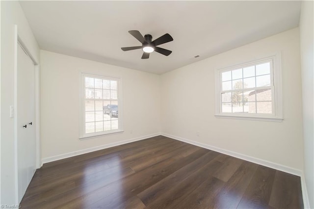 unfurnished bedroom featuring dark wood finished floors, multiple windows, and baseboards