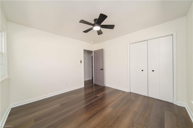 unfurnished bedroom featuring dark wood-style floors, baseboards, and a closet