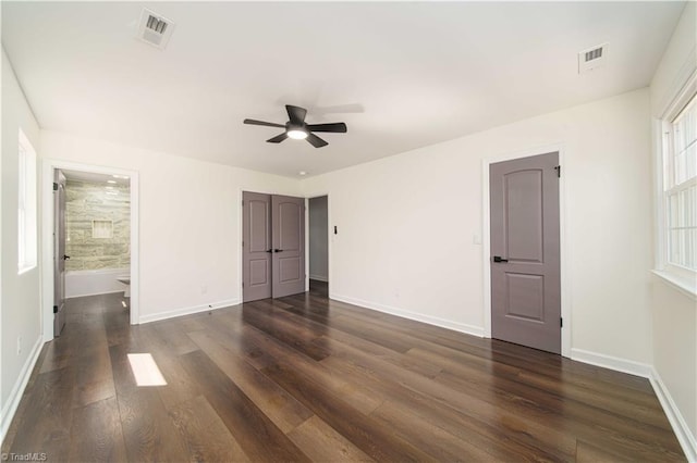 unfurnished bedroom with visible vents, baseboards, ensuite bath, and dark wood-style flooring