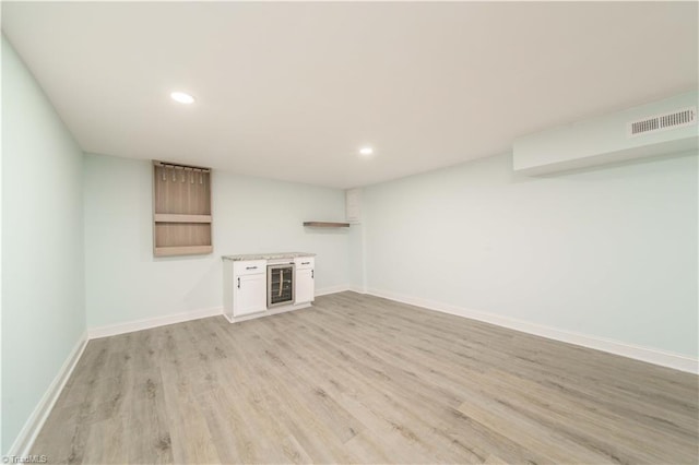 finished basement with visible vents, recessed lighting, wine cooler, light wood finished floors, and baseboards