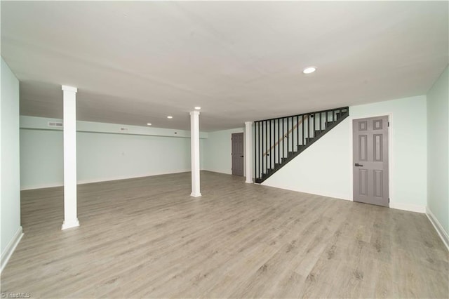 finished basement featuring light wood finished floors, visible vents, baseboards, stairs, and recessed lighting