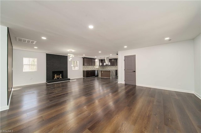 unfurnished living room featuring visible vents, a brick fireplace, baseboards, recessed lighting, and dark wood-style floors