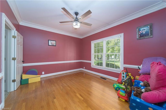 rec room with visible vents, baseboards, a ceiling fan, wood finished floors, and ornamental molding