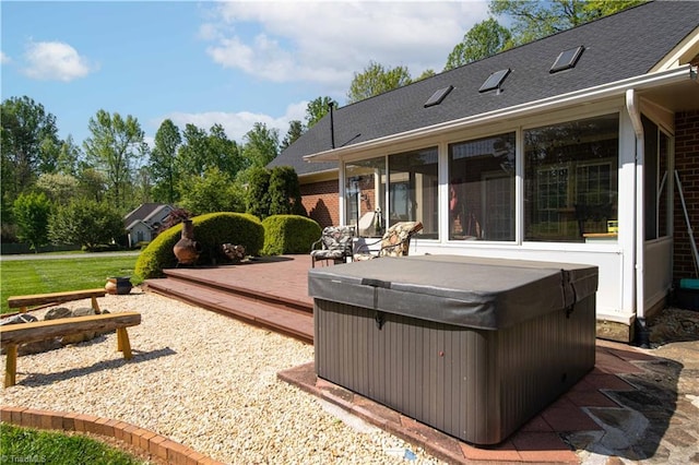 rear view of property featuring a wooden deck, brick siding, a hot tub, and a shingled roof