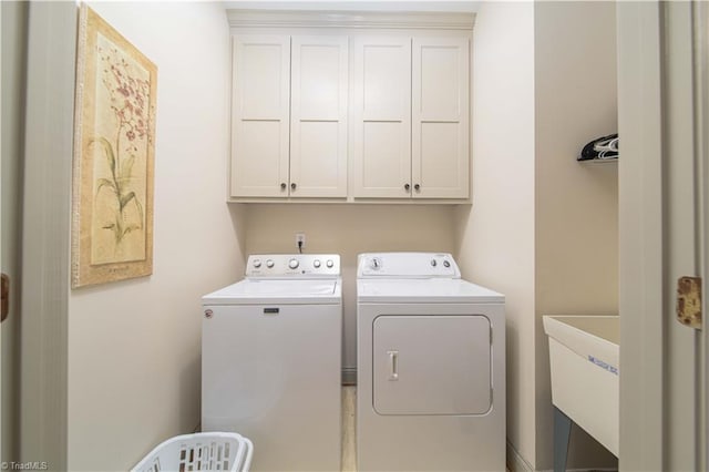 laundry area with separate washer and dryer, a sink, and cabinet space