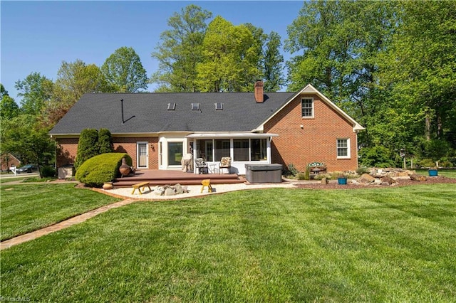 rear view of house featuring a lawn, a sunroom, a deck, and brick siding