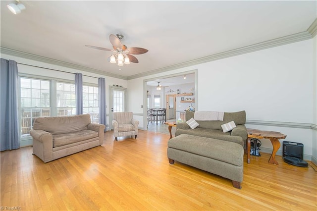 living area featuring ornamental molding, a ceiling fan, light wood-style flooring, and a healthy amount of sunlight