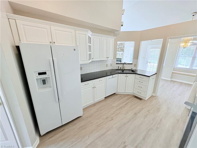 204 Maplewood Ct, Trinity, NC 27370 - kitchen featuring white appliances, light wood-style flooring, dark countertops, a peninsula, and backsplash