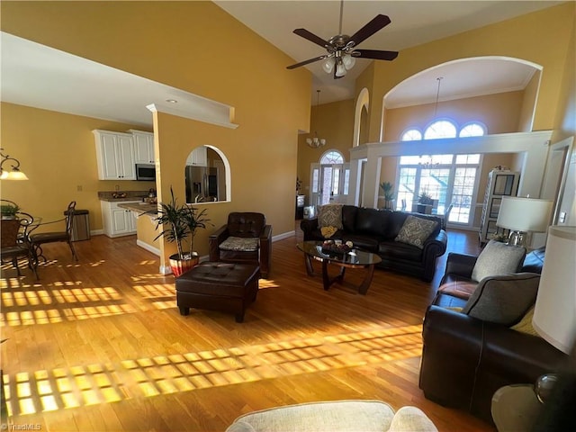 living room with ceiling fan, light hardwood / wood-style floors, high vaulted ceiling, and ornamental molding