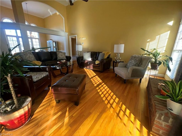 living room with a high ceiling, crown molding, a healthy amount of sunlight, and hardwood / wood-style floors