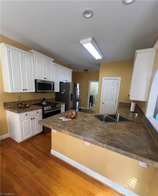 kitchen featuring sink, kitchen peninsula, white cabinets, and stainless steel appliances