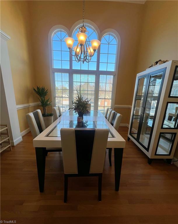 dining space with a towering ceiling, dark hardwood / wood-style flooring, and a notable chandelier