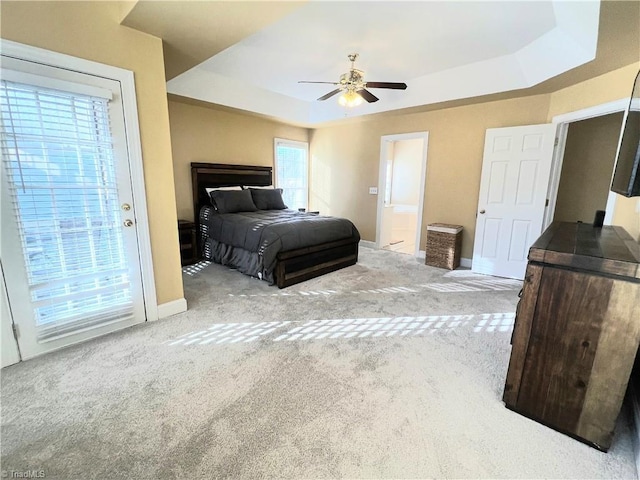 carpeted bedroom featuring a raised ceiling, access to exterior, and ceiling fan