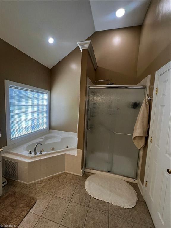 bathroom with shower with separate bathtub, lofted ceiling, and tile patterned flooring