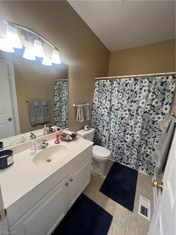 bathroom featuring toilet, vanity, tile patterned flooring, and curtained shower