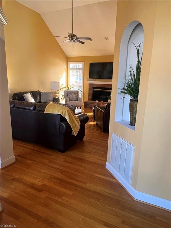 living room with a fireplace, ceiling fan, dark wood-type flooring, and lofted ceiling