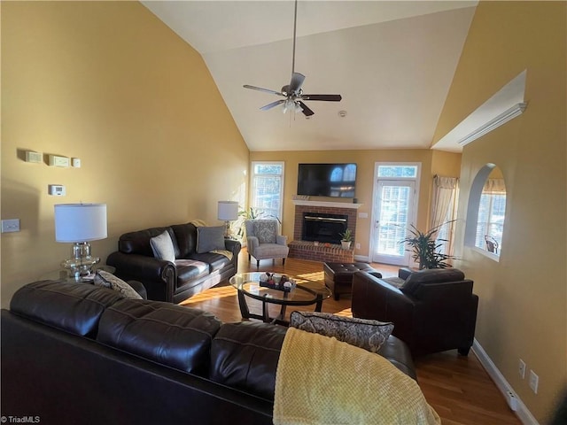 living room featuring vaulted ceiling, a healthy amount of sunlight, a fireplace, and hardwood / wood-style flooring