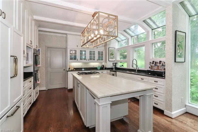 kitchen featuring a sink, hanging light fixtures, a kitchen island, and white cabinetry