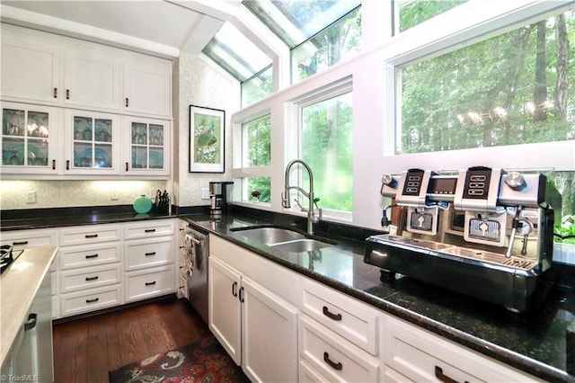 kitchen featuring dark wood-type flooring, glass insert cabinets, white cabinets, a sink, and dark stone counters