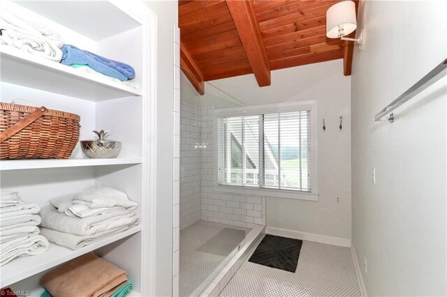 bathroom with wooden ceiling, vaulted ceiling with beams, tile patterned flooring, and tiled shower