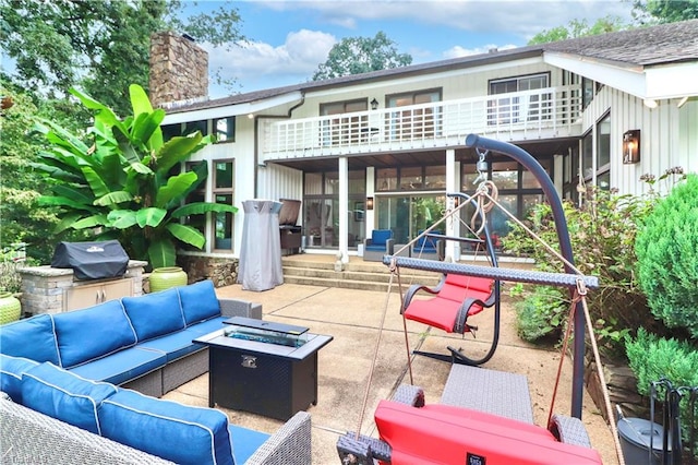 view of patio / terrace with a balcony and an outdoor living space with a fire pit