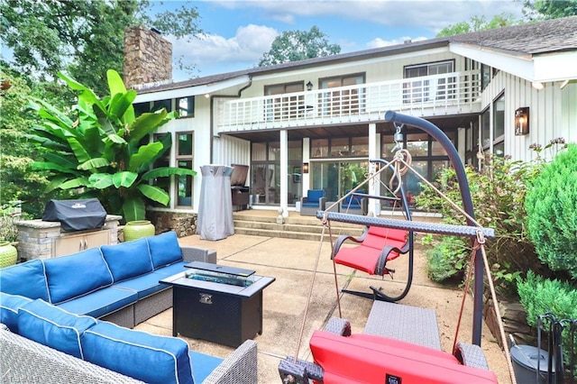 rear view of house with a patio area, a chimney, board and batten siding, and an outdoor living space with a fire pit