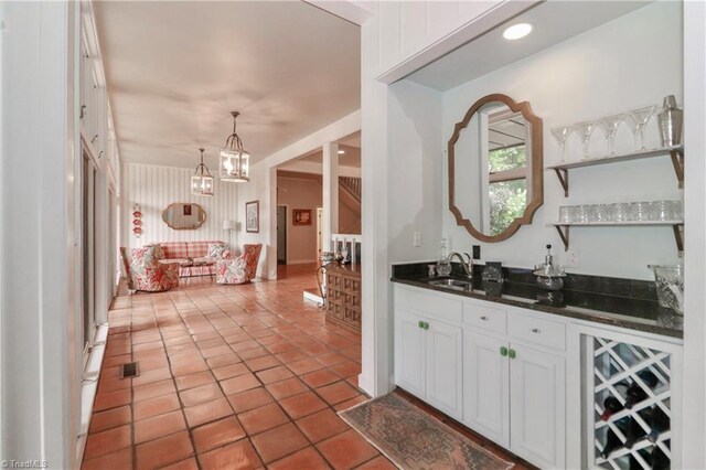 bar featuring decorative light fixtures, white cabinetry, sink, light tile patterned floors, and a notable chandelier