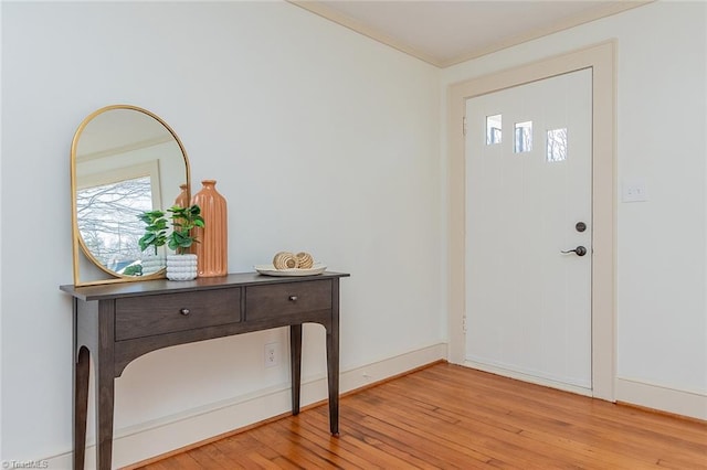 entryway with baseboards, wood-type flooring, and crown molding