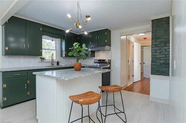 kitchen featuring light wood-style flooring, stainless steel range with electric cooktop, a sink, green cabinetry, and under cabinet range hood