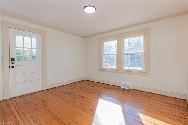 empty room with hardwood / wood-style flooring, plenty of natural light, visible vents, and baseboards