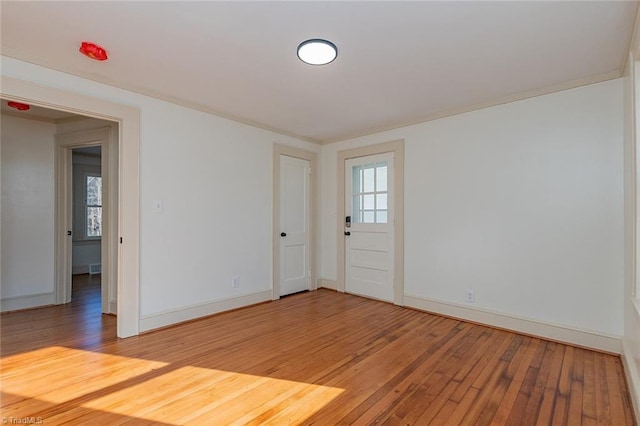 unfurnished room with ornamental molding, baseboards, and light wood finished floors