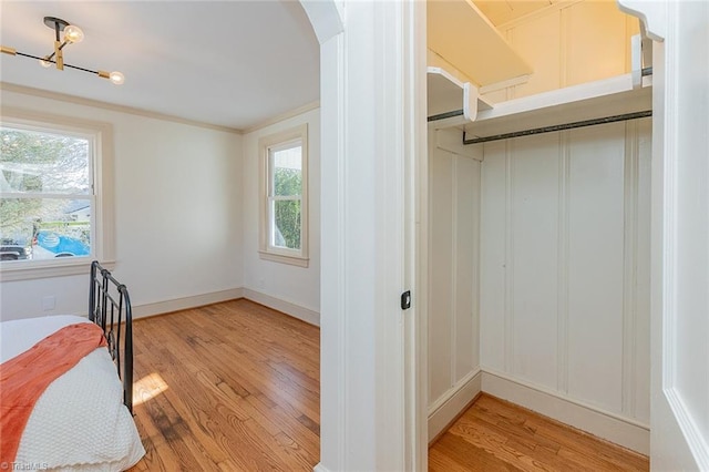 bedroom featuring arched walkways, ornamental molding, baseboards, and light wood-style floors