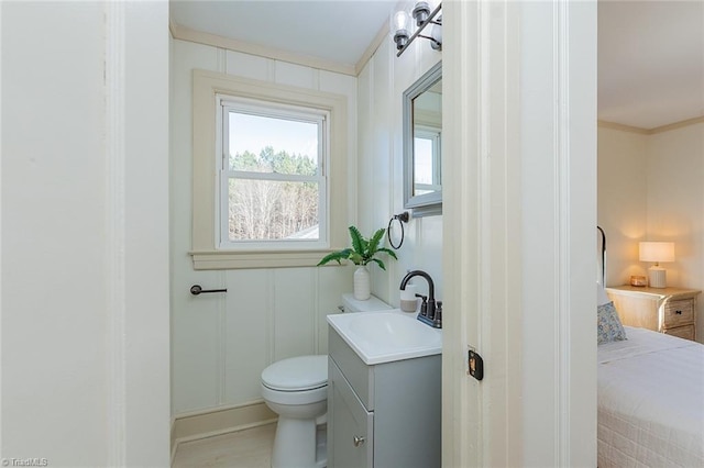 bathroom with toilet, crown molding, and vanity