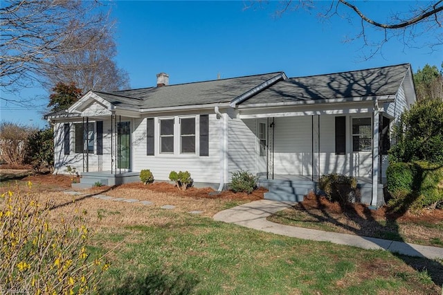 view of front of house with a porch, a chimney, and a front yard