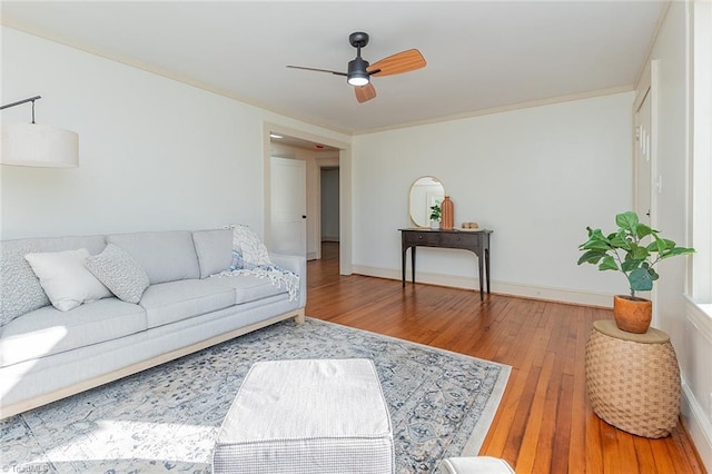 living room with a ceiling fan, wood-type flooring, crown molding, and baseboards