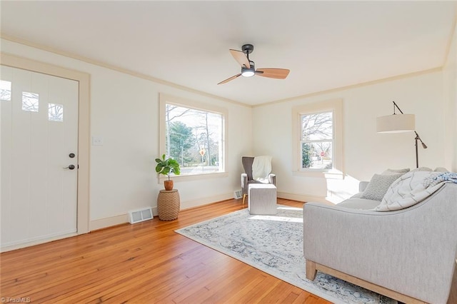 sitting room featuring baseboards, visible vents, ceiling fan, crown molding, and light wood-style floors