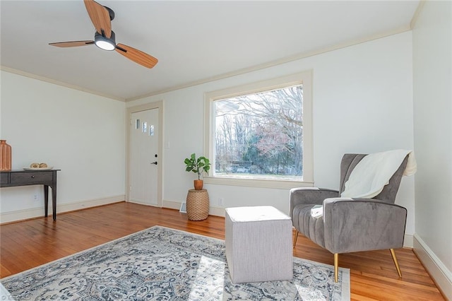 sitting room with ornamental molding, wood finished floors, and baseboards