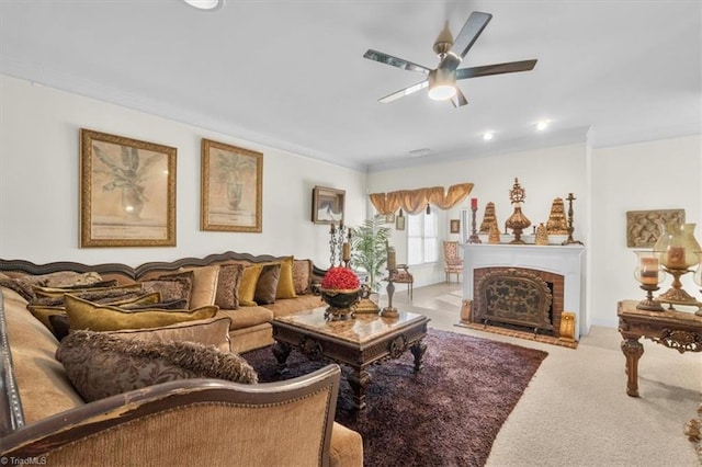 living room featuring ceiling fan, a fireplace, ornamental molding, and carpet floors