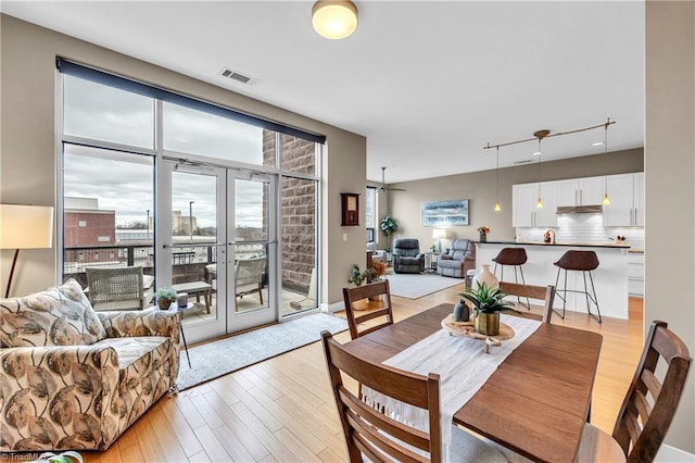 dining room featuring light wood-style floors, visible vents, and french doors