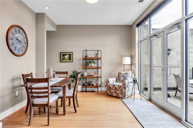 dining room with expansive windows, french doors, light wood-style flooring, and baseboards