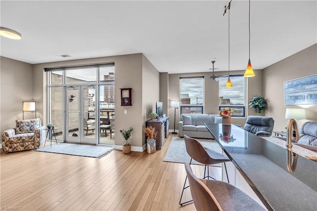 living room featuring light wood-style floors, plenty of natural light, baseboards, and french doors