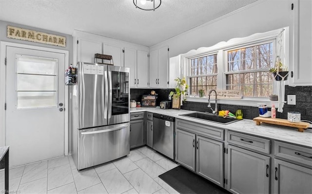 kitchen with appliances with stainless steel finishes, gray cabinets, light countertops, and a sink