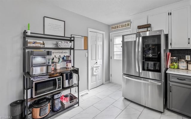 kitchen with stainless steel appliances, light countertops, gray cabinetry, white cabinets, and a textured ceiling